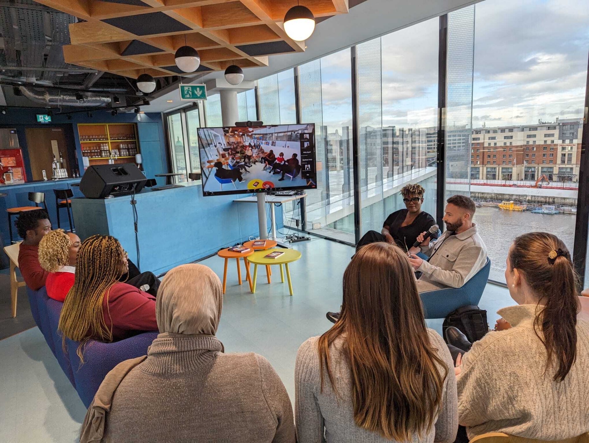 A live in-person and remote training session with experienced professionals listening to the speaker.